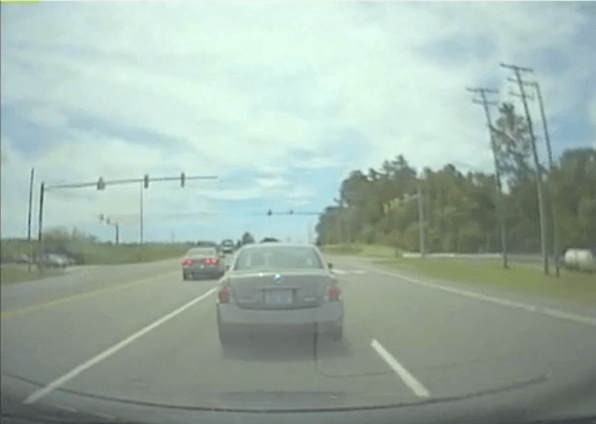 Two cars on a road near a stop light