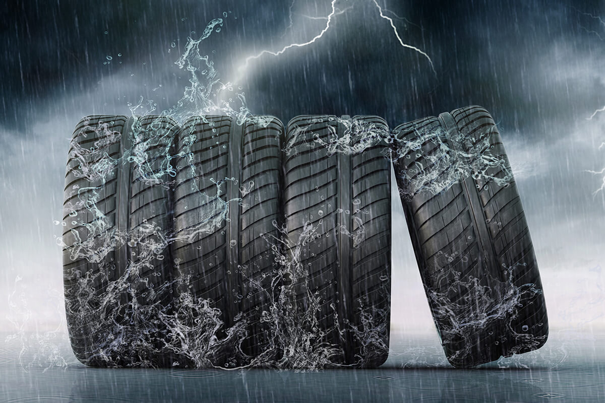 Four tires sitting in the rain with lightning strikes in the background